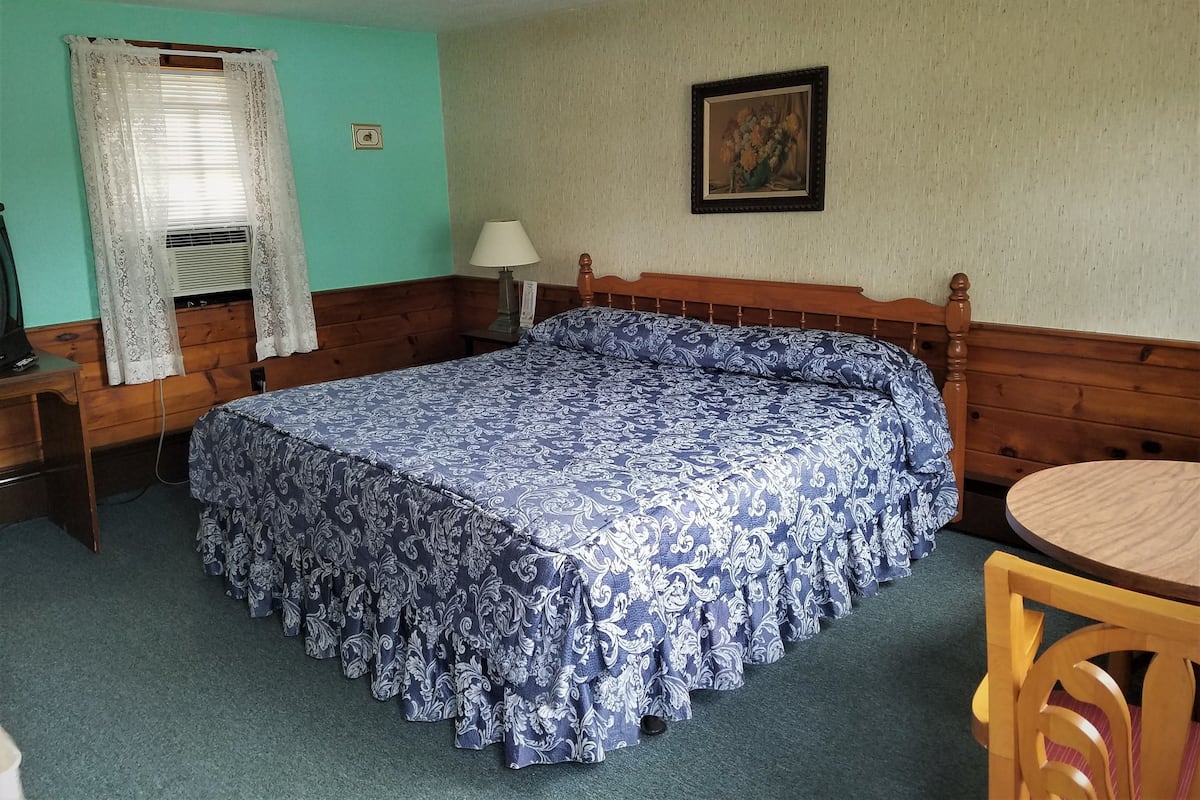 Une pièce comprenant un lit, un bureau, une chaise, une lampe et un tableau accroché au mur.