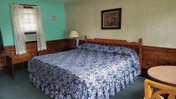A room with a bed, a desk, a chair, a lamp, and a picture on the wall.