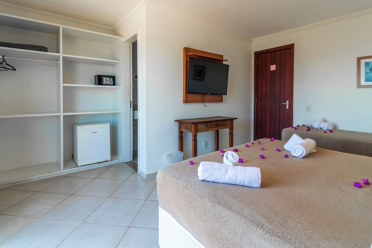 Ein Hotelzimmer mit Bett, Fernseher, Holztisch, Kleiderschrank und Tür.