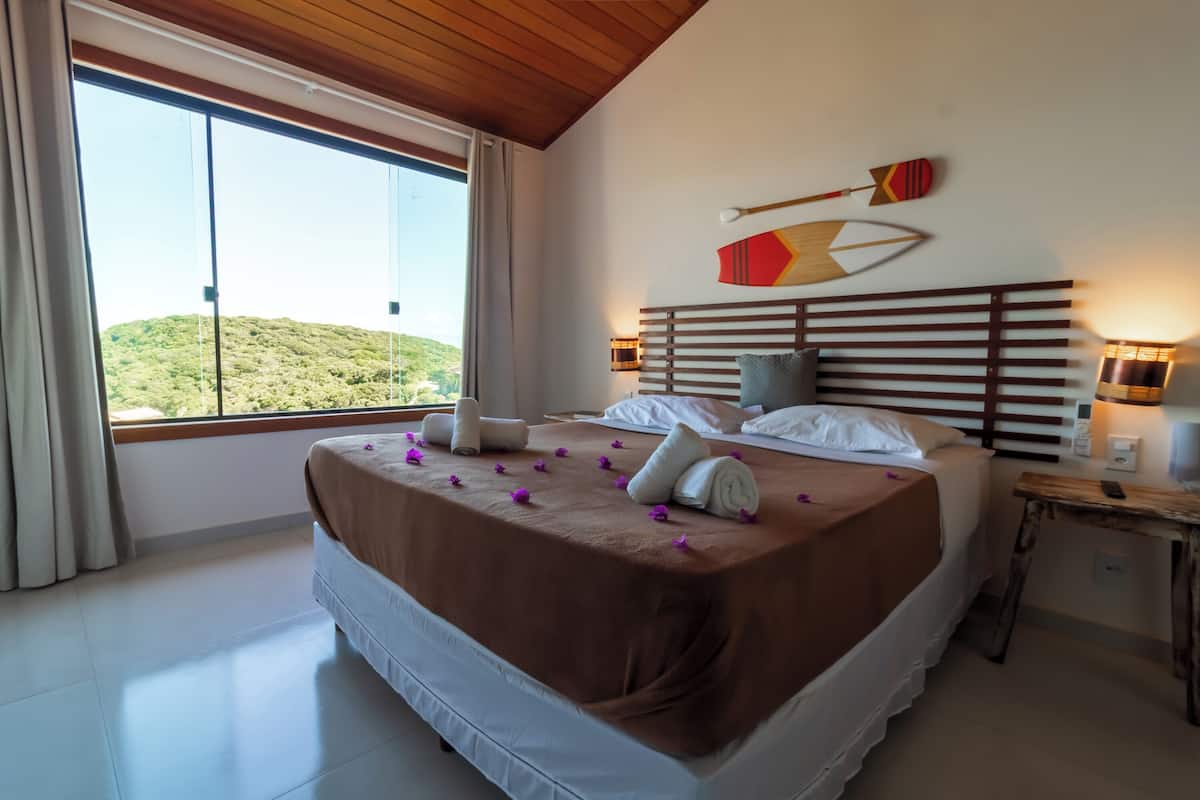 Ein Schlafzimmer mit einem großen Bett, Blick auf einen Hügel und zwei Wandlampen.