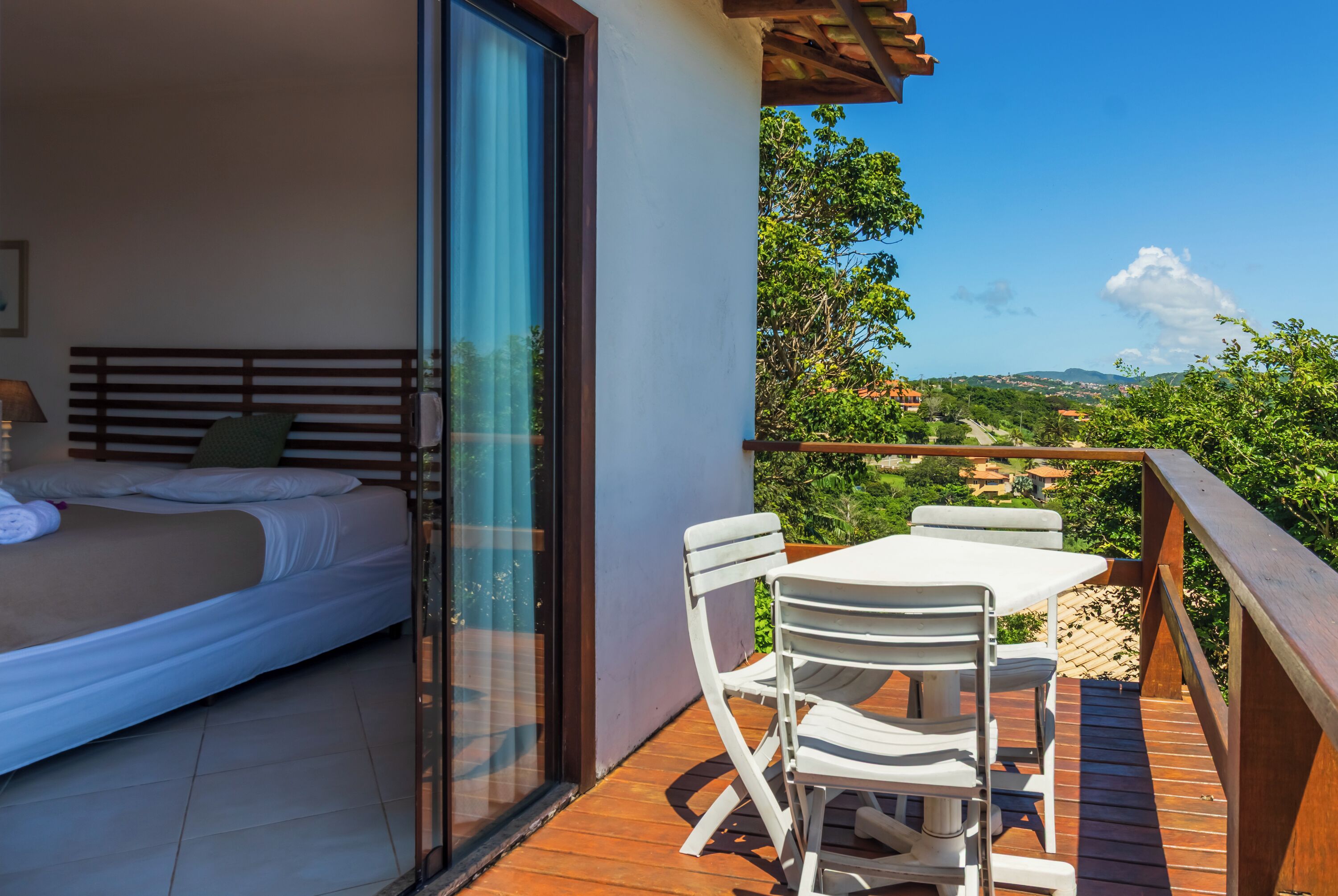 Un balcon avec un lit et une table entourée de chaises, offrant une vue sur un paysage magnifique.