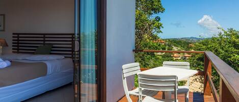 Un balcon avec un lit et une table entourée de chaises, offrant une vue sur un paysage magnifique.