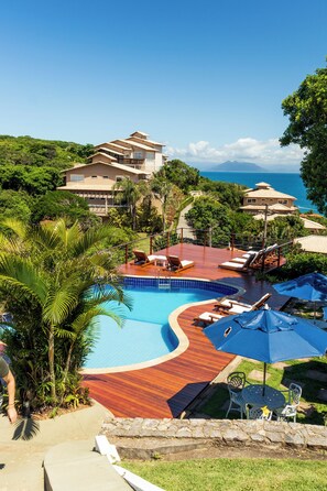A resort with a swimming pool, lounge chairs, and a view of the ocean. - Pousada La Proeza (Búzios)