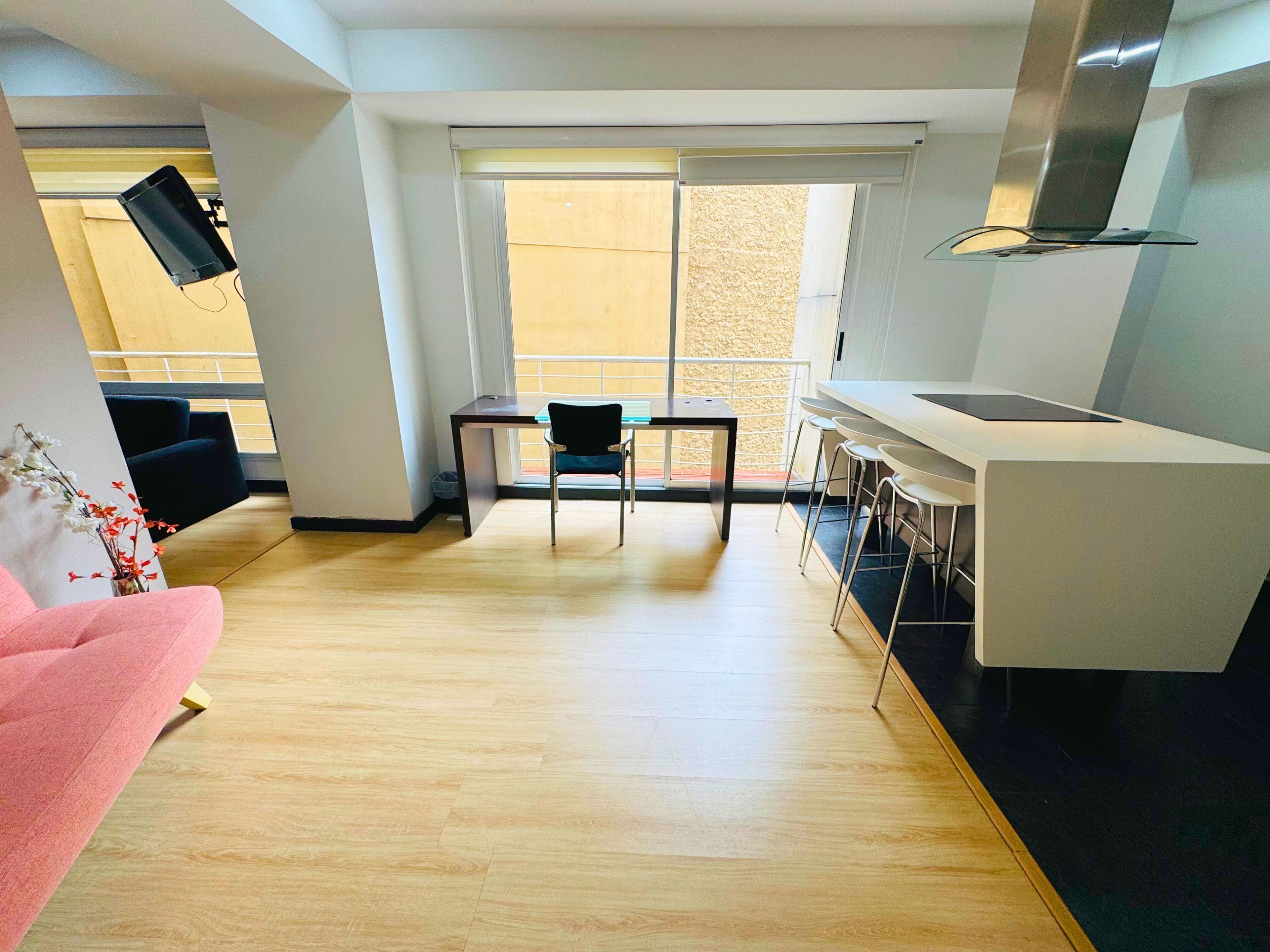 A modern apartment with a dining area, kitchen, and a balcony with a view.
