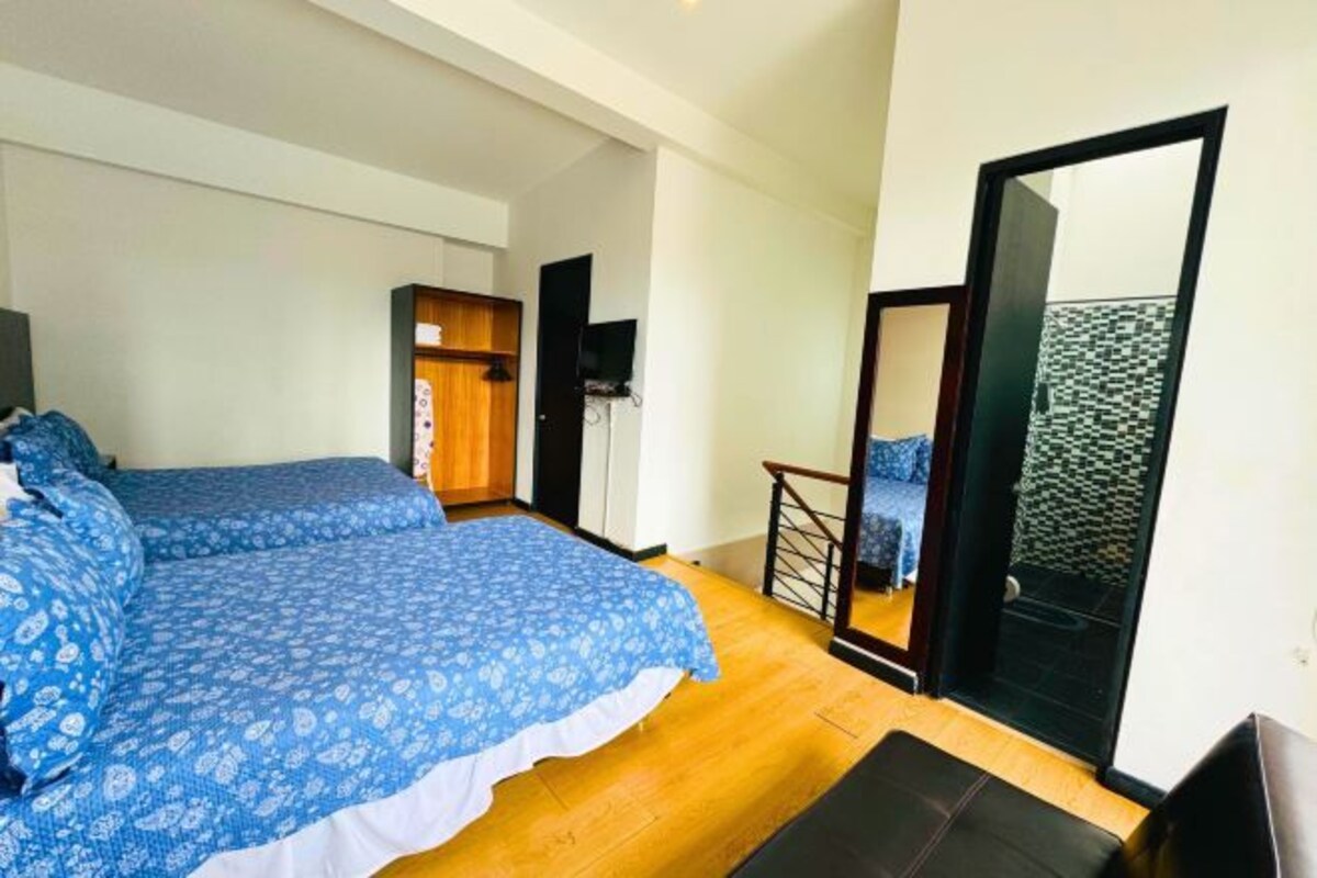 Un dormitorio con dos camas, piso de madera, televisor y balcón con vistas.