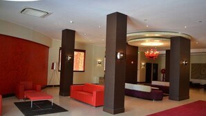 A modern lobby with red and brown furnishings, a red carpet, and a chandelier. - Jardy Hôtel & Suites (Algiers)