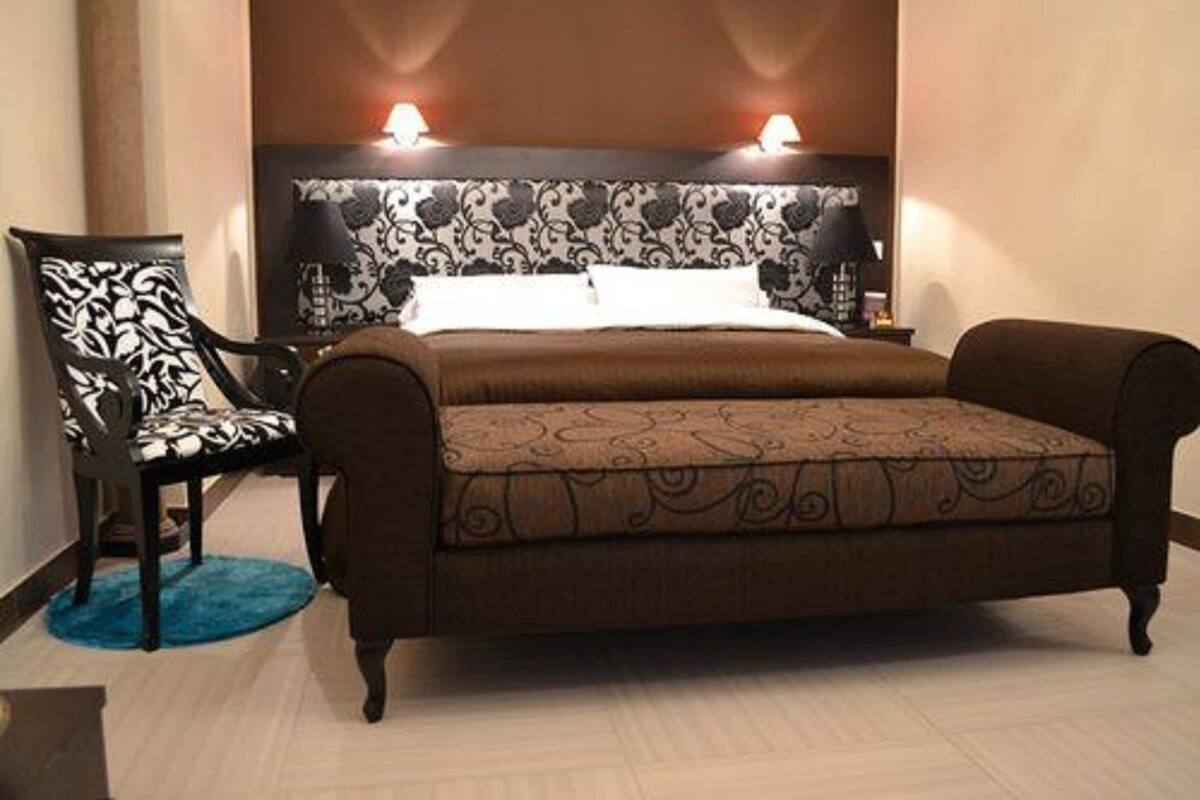 A bedroom with a bed, two bedside lamps, a chair, and a patterned headboard.