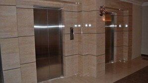 A modern elevator with a metallic finish, set in a hallway with beige marble walls and a polished floor. - Jardy Hôtel & Suites (Algiers)