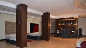 A modern hotel lobby with a reception desk, a seating area, and a large artwork on the wall. - Jardy Hôtel & Suites (Algiers)