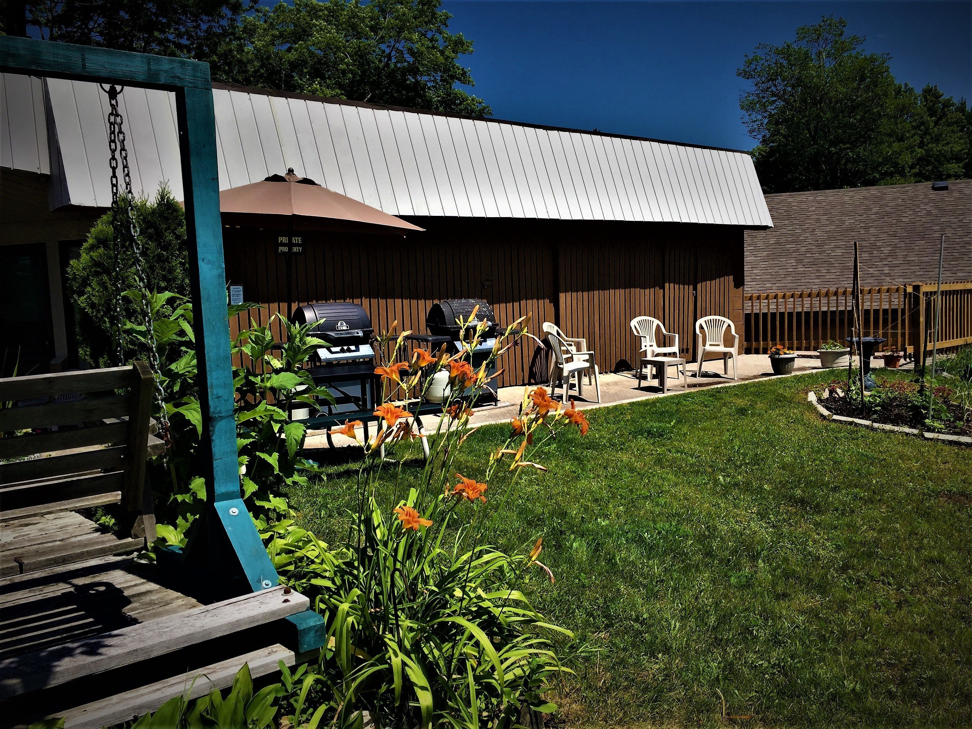 Un espace patio avec des sièges d’extérieur, un barbecue et un jardin clôturé.