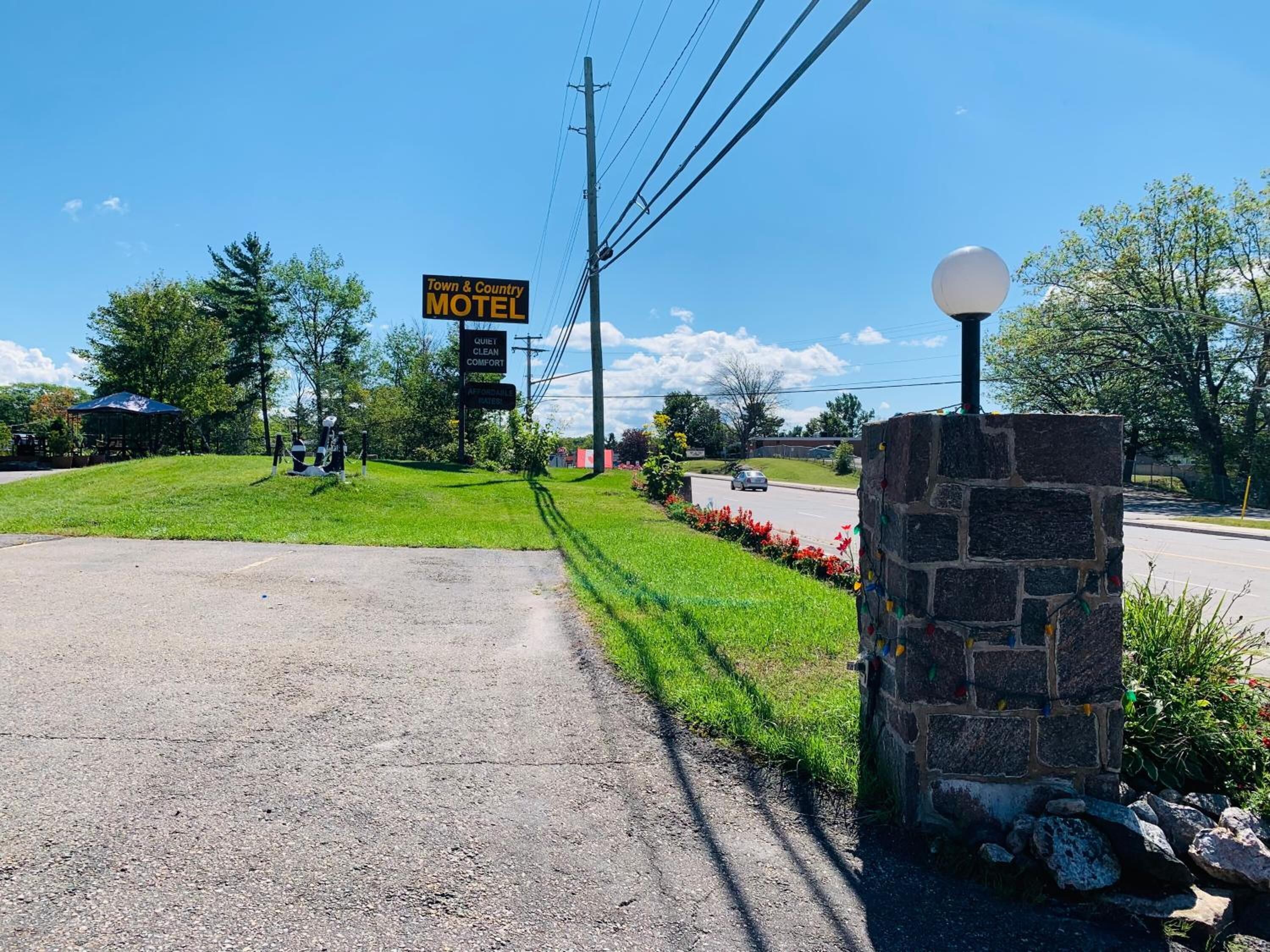 A motel sign with a clear, welcoming entrance and a stone wall with a spherical light fixture.