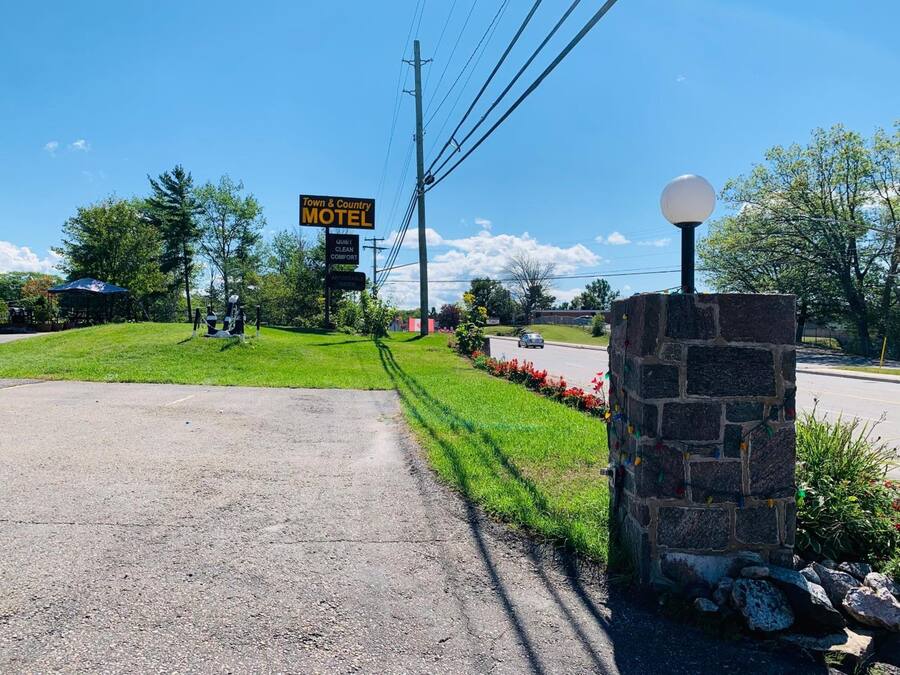 A motel sign with a clear, welcoming entrance and a stone wall with a spherical light fixture.