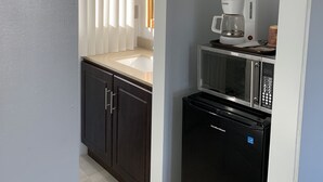 A compact kitchen with a refrigerator, microwave, and coffee maker. - Town and Country Motel (Parry Sound)