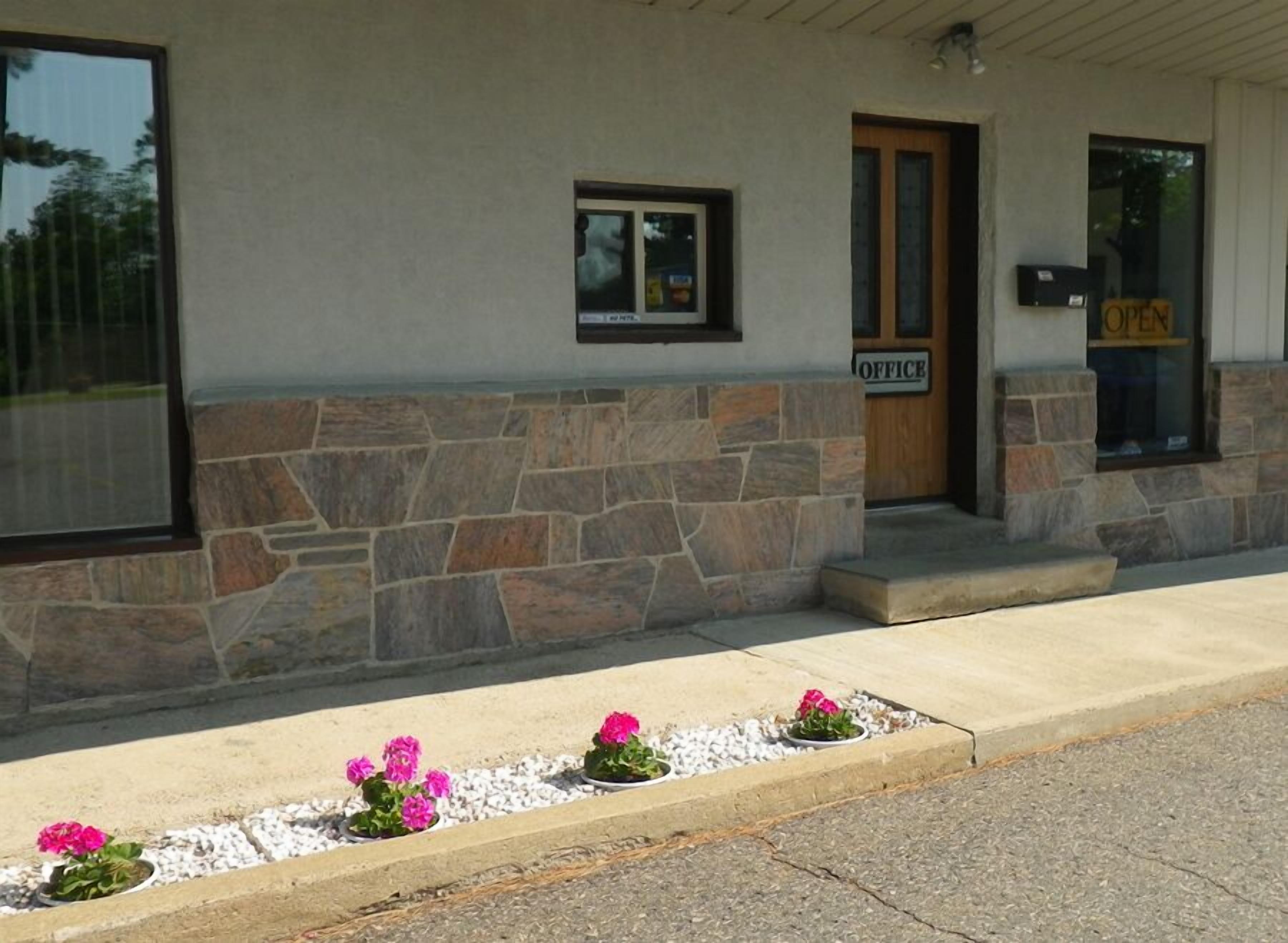 A building with a stone facade, a wooden door, and a window with a sign that reads "OFFICE".