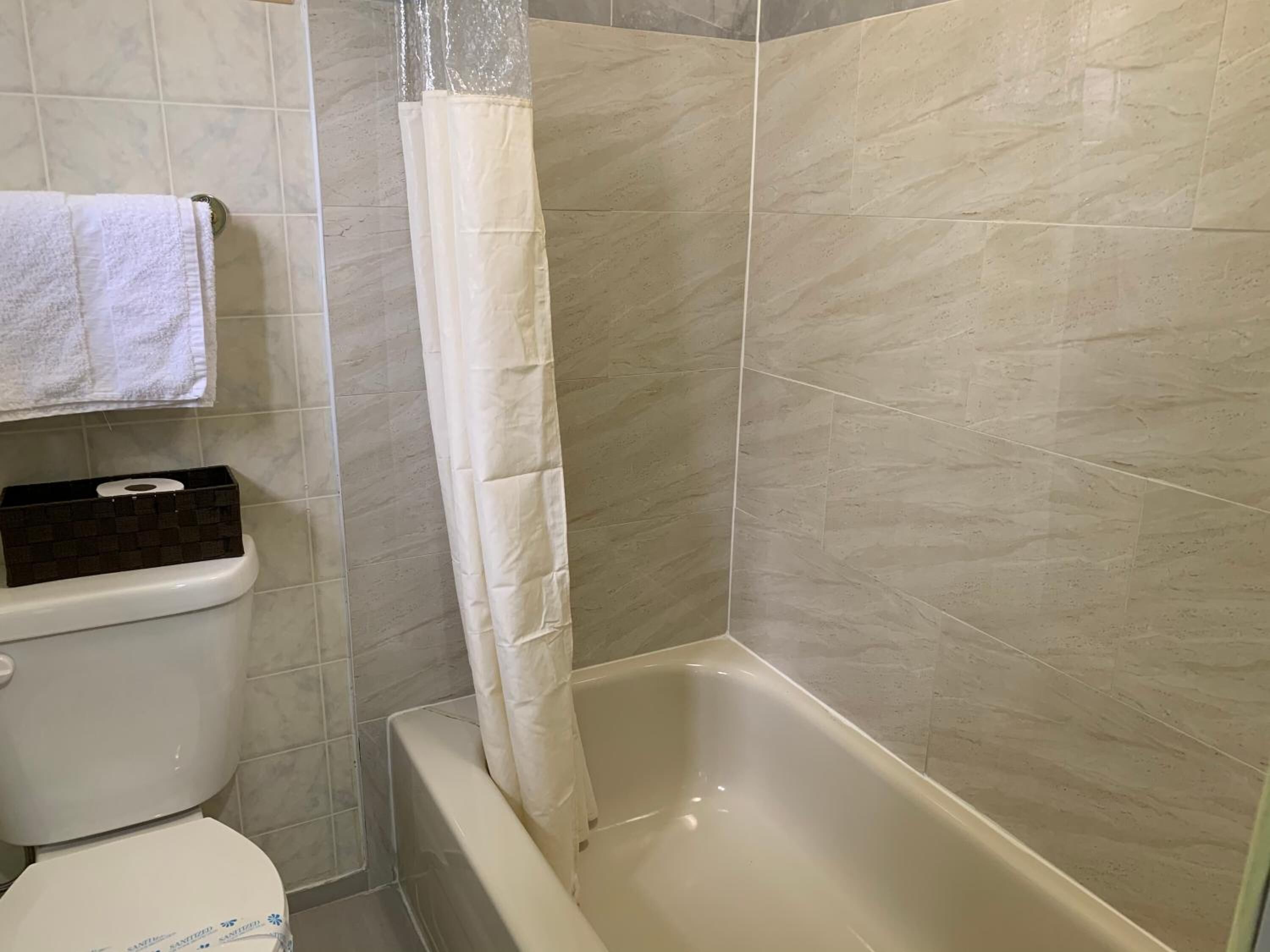 Un baño con inodoro, bañera y cortina de ducha.