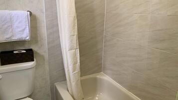 Un baño con inodoro, bañera y cortina de ducha.