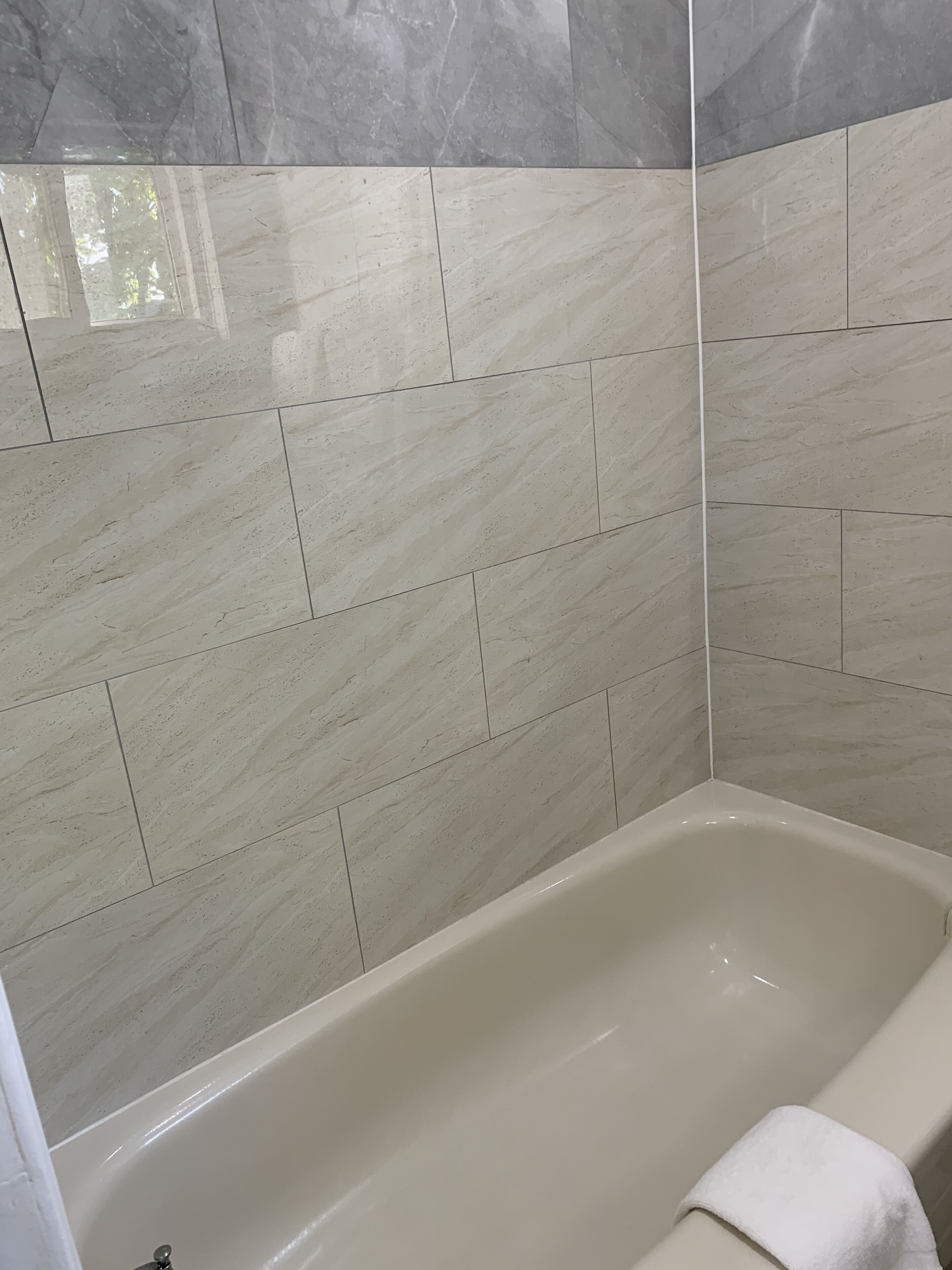 A bathroom with a bathtub, tiled walls, and a towel on the tub.