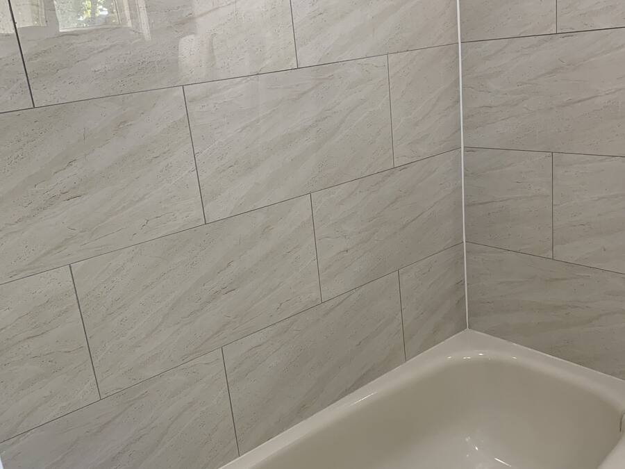 A bathroom with a bathtub, tiled walls, and a towel on the tub.