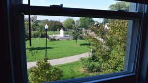 A view through a window of a grassy area with a path, a lamppost, and some trees.