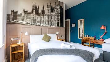 Une chambre d’hôtel avec un grand lit, une table de chevet avec une lampe, une commode et un miroir.
