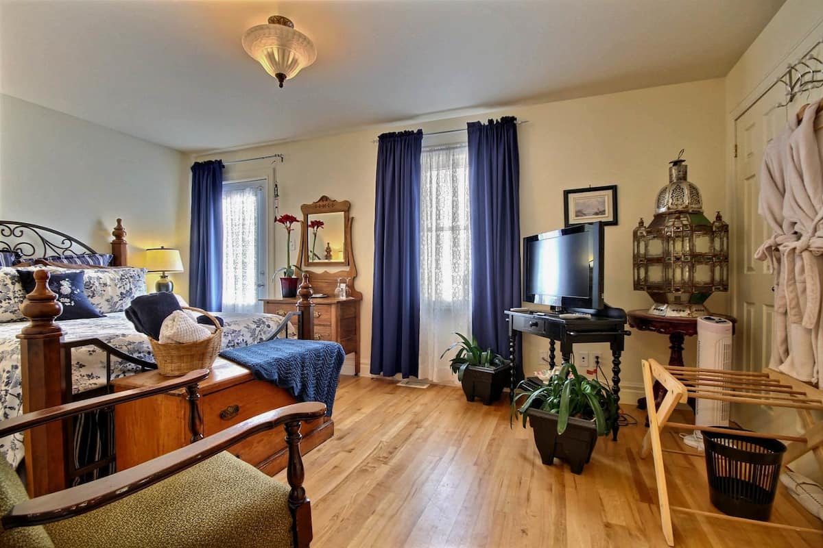 Tunnelmallinen makuuhuone, jossa on puinen sänky, lipasto, televisio ja lamppu.