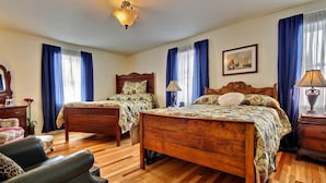 Un dormitorio con dos camas de madera, un aparador de madera, una silla y un escritorio.