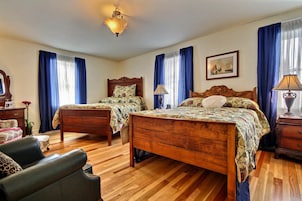 A bedroom with two wooden beds, a wooden dresser, a chair, and a desk.