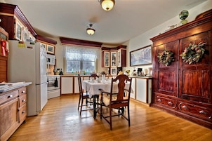 A kitchen with wooden cabinets, a dining table, and a refrigerator.