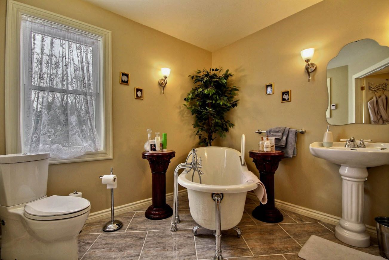 Une salle de bain comprenant des toilettes, une baignoire sur pieds, un lavabo et un grand miroir.