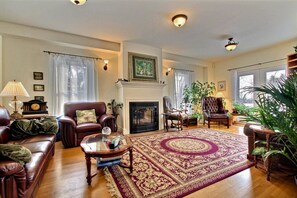 A spacious living room with a fireplace, leather sofas, a coffee table, and a large rug. - Terrace Green Bed & Breakfast (North Dundas)
