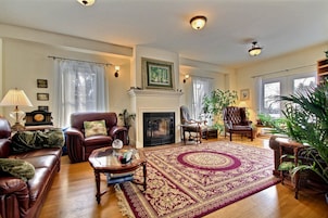A spacious living room with a fireplace, leather sofas, a coffee table, and a large rug.
