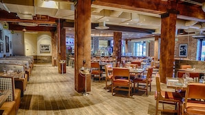 A restaurant with wooden floors, brick walls, and a bar area. Tables and chairs are arranged for dining. - Hard Rock Hotel & Casino Sioux City (Sioux City)