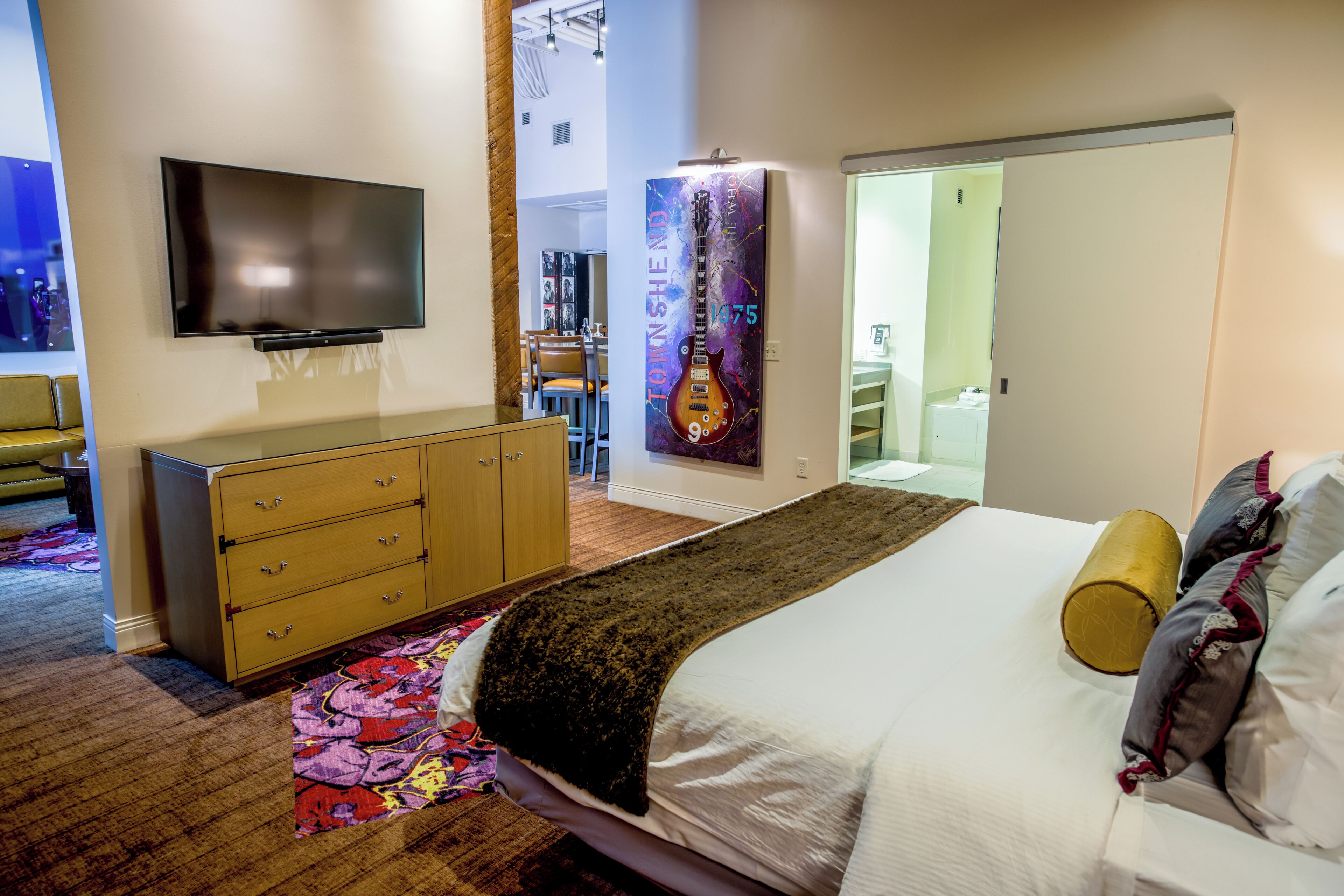 A bedroom with a bed, a dresser, a TV, and a poster on the wall.