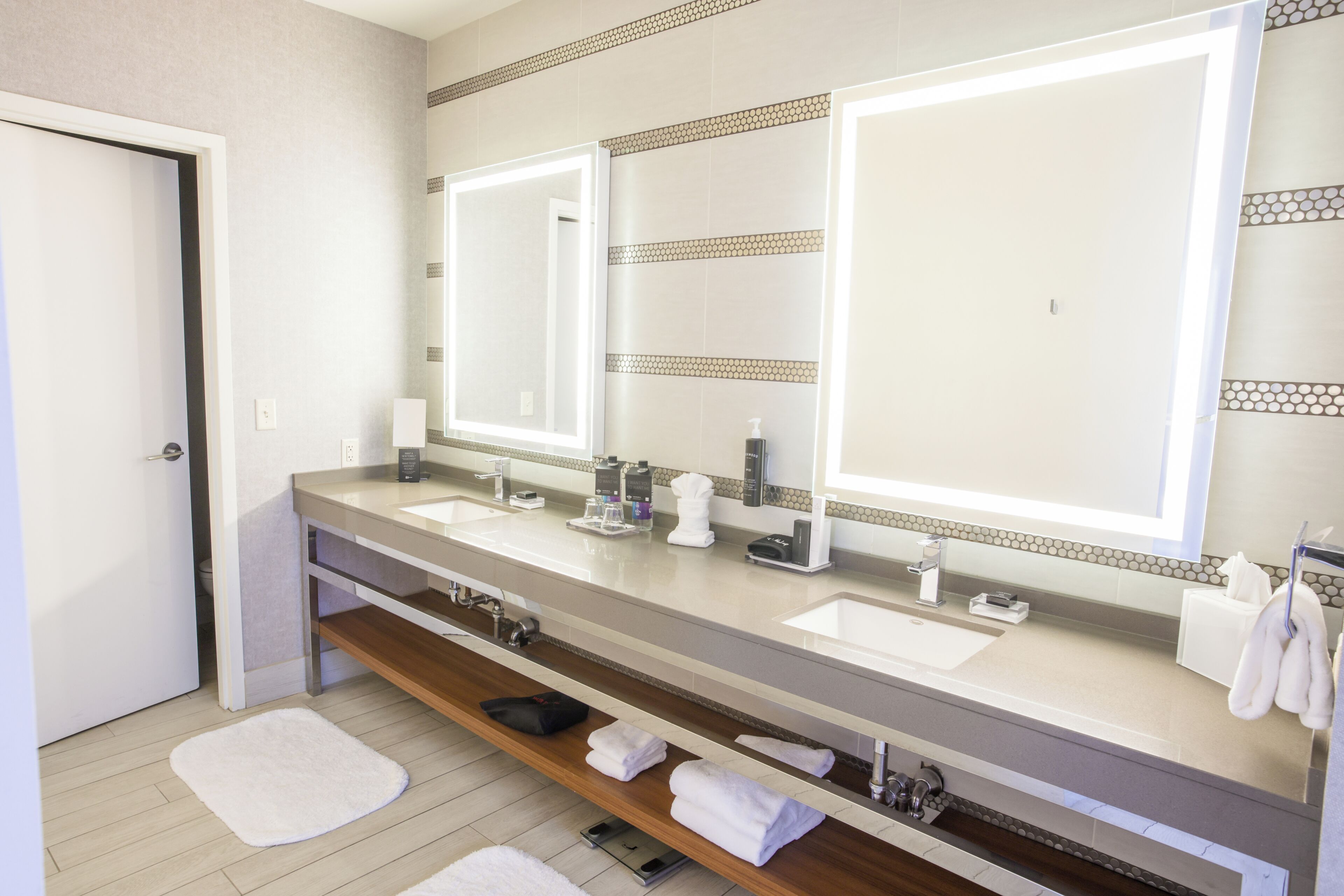 Un baño moderno con dos lavabos, un espejo grande y un perchero para toallas.