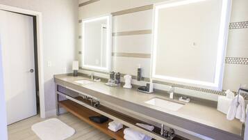 Un baño moderno con dos lavabos, un espejo grande y un perchero para toallas.
