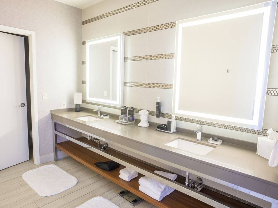 Un baño moderno con dos lavabos, un espejo grande y un perchero para toallas.