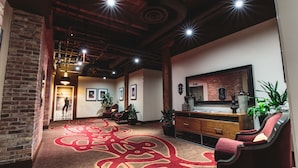 A spacious lobby with a patterned carpet, a brick wall, and a wooden ceiling. - Hard Rock Hotel & Casino Sioux City (Sioux City)