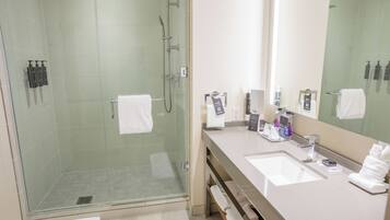 Een moderne badkamer met een douchecabine van glas, twee wasbakken en een grote spiegel.