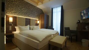 Habitación de hotel con una cama grande, un escritorio, una silla y un televisor.