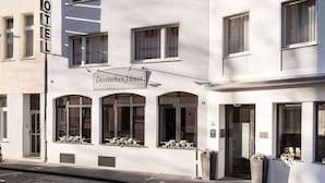 Een hotelgebouw met een bord waarop “Deutsches Haus” staat en een “HOTEL” bord boven de ingang.