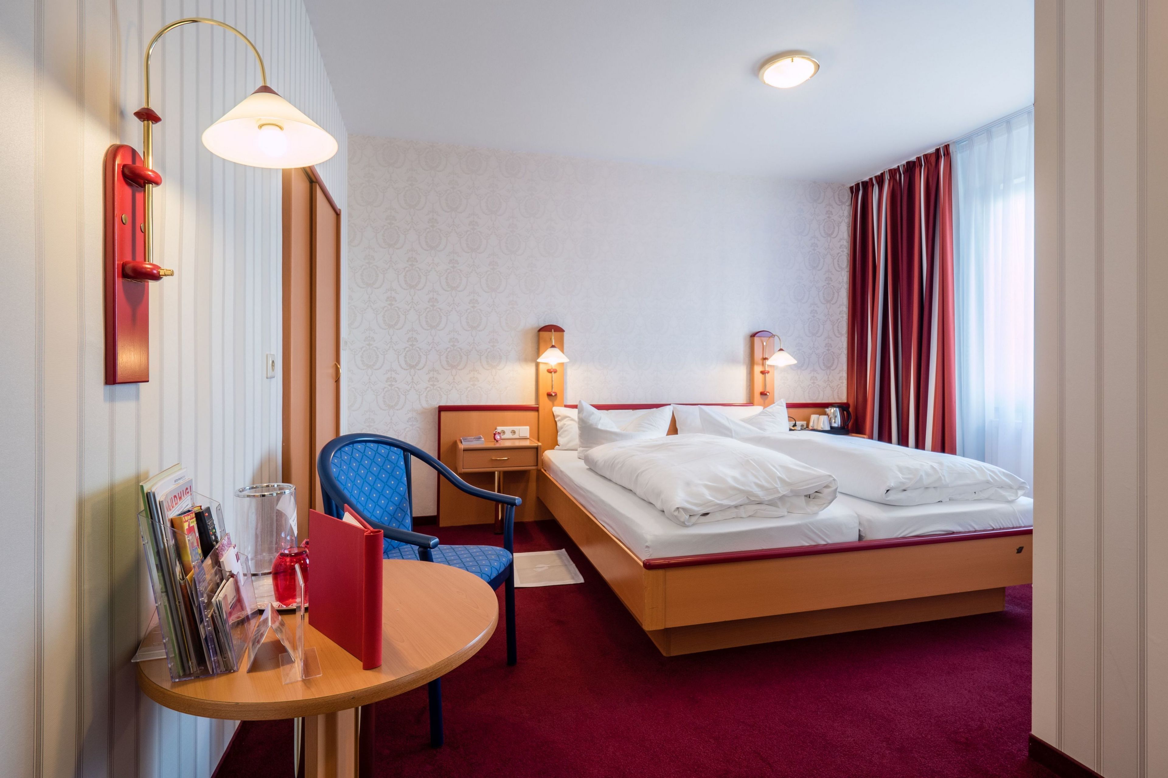 Une chambre d’hôtel comprenant un lit, des tables de chevet, une chaise, un bureau et une lampe.