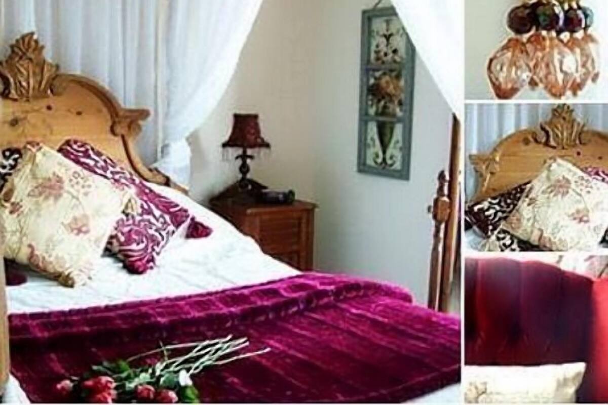 A bedroom with a wooden bed, a purple bedspread, and a nightstand with a lamp.