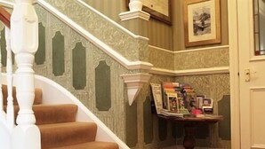 Una escalera con barandales ornamentados y un rellano alfombrado.