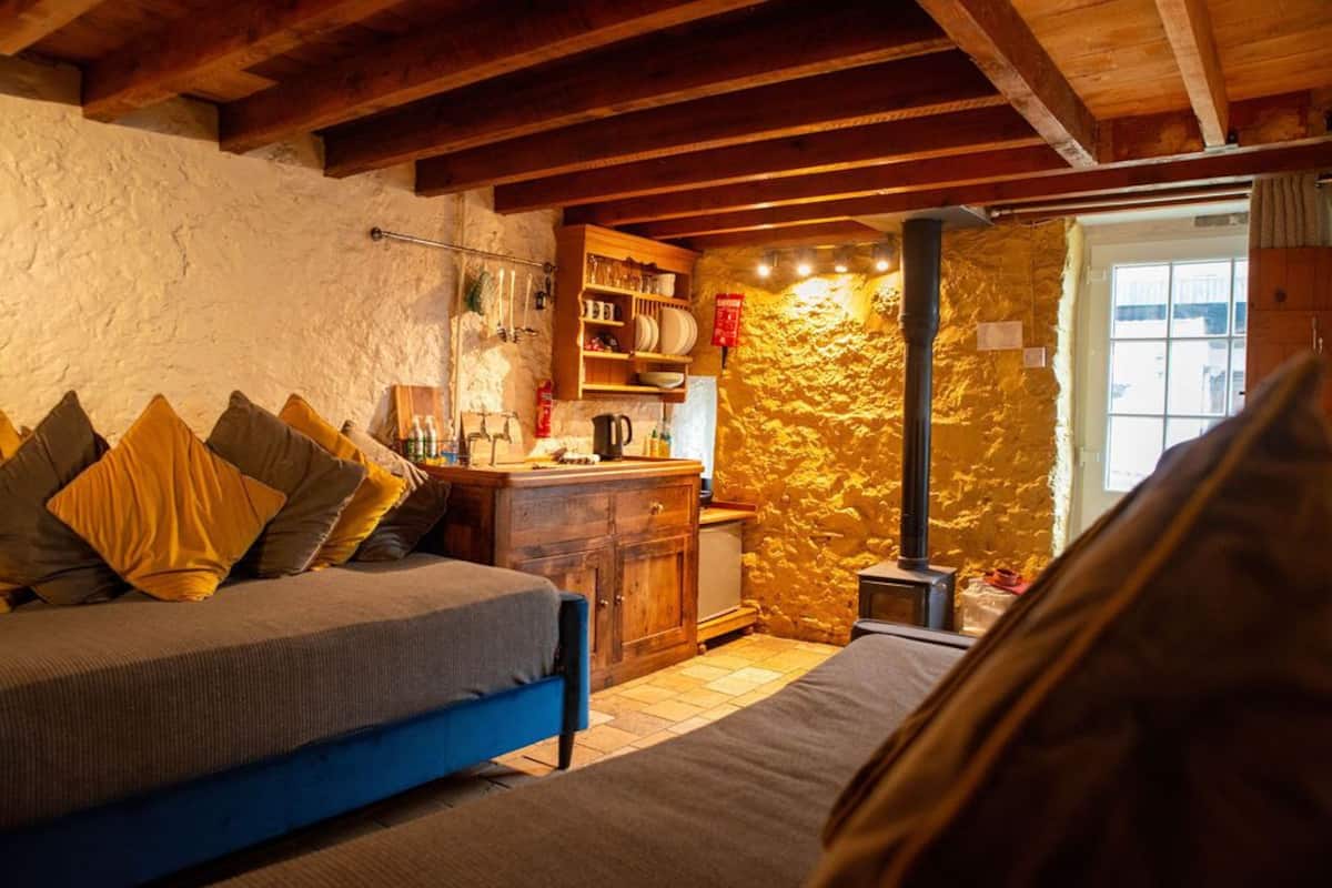 A cozy bedroom with a bed, a wooden dresser, and a stone wall.