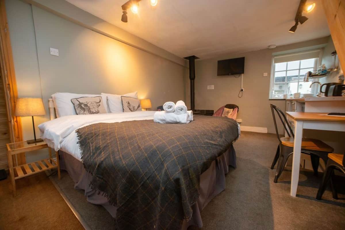 A bedroom with a bed, bedside table, lamp, and a desk with chairs.
