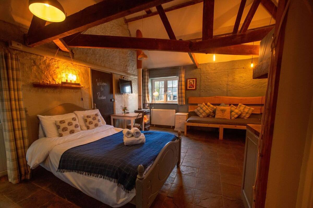 A cozy bedroom with a bed, a bench, and a desk.