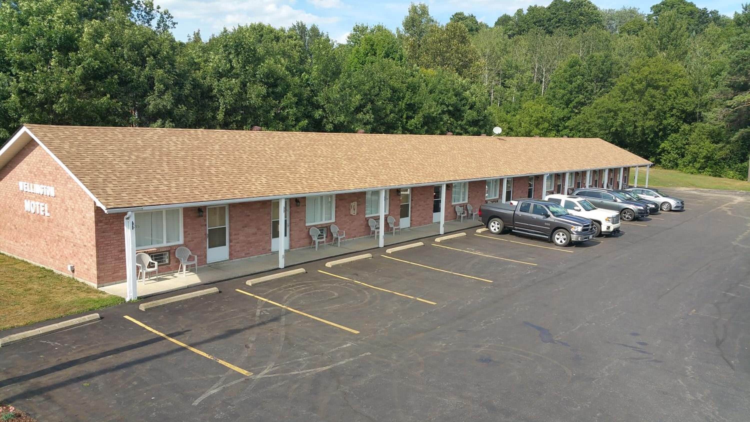 A motel with a brick facade, multiple rooms, and a parking lot with several cars.