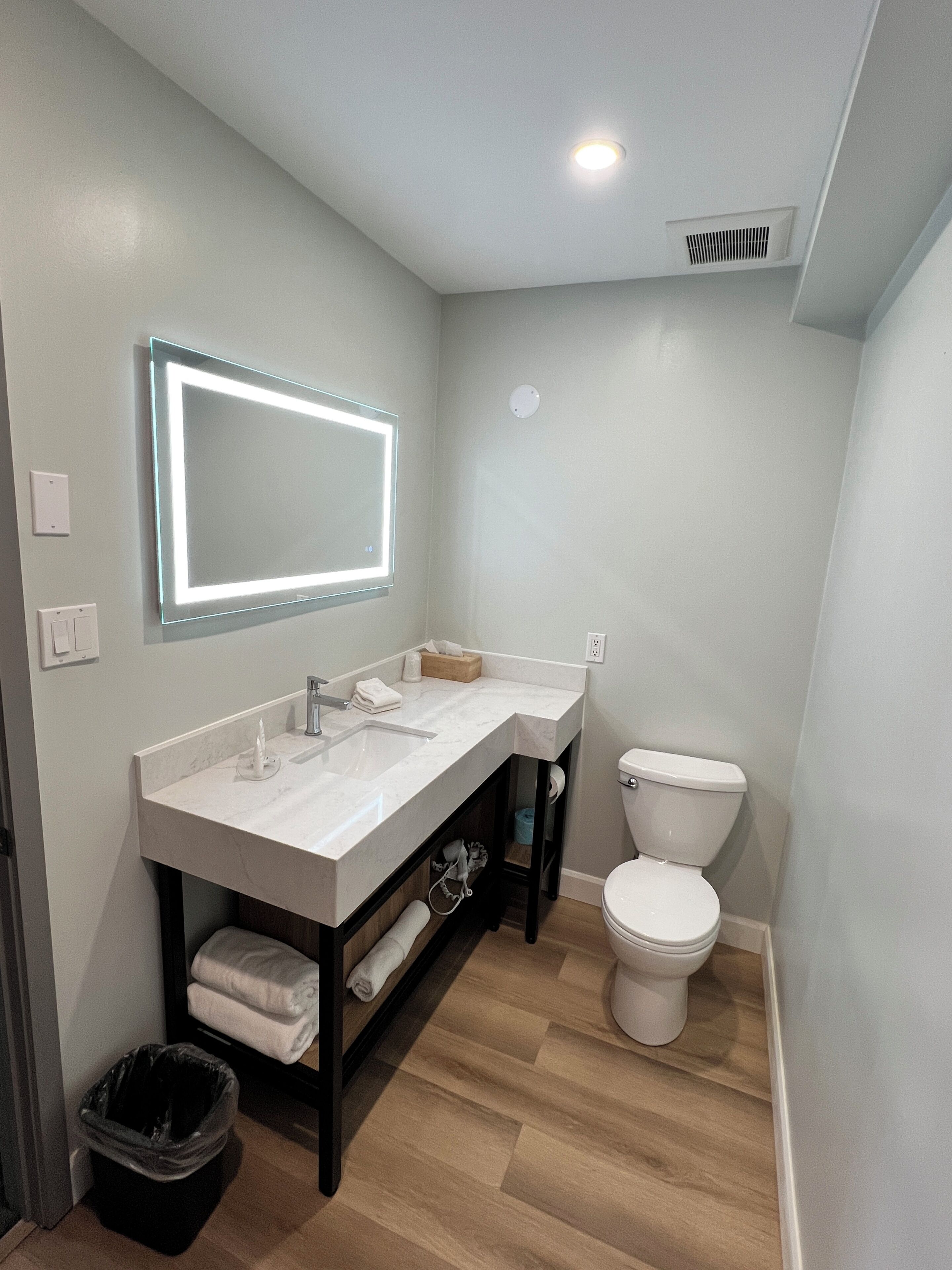 A bathroom with a white sink, mirror, and toilet.