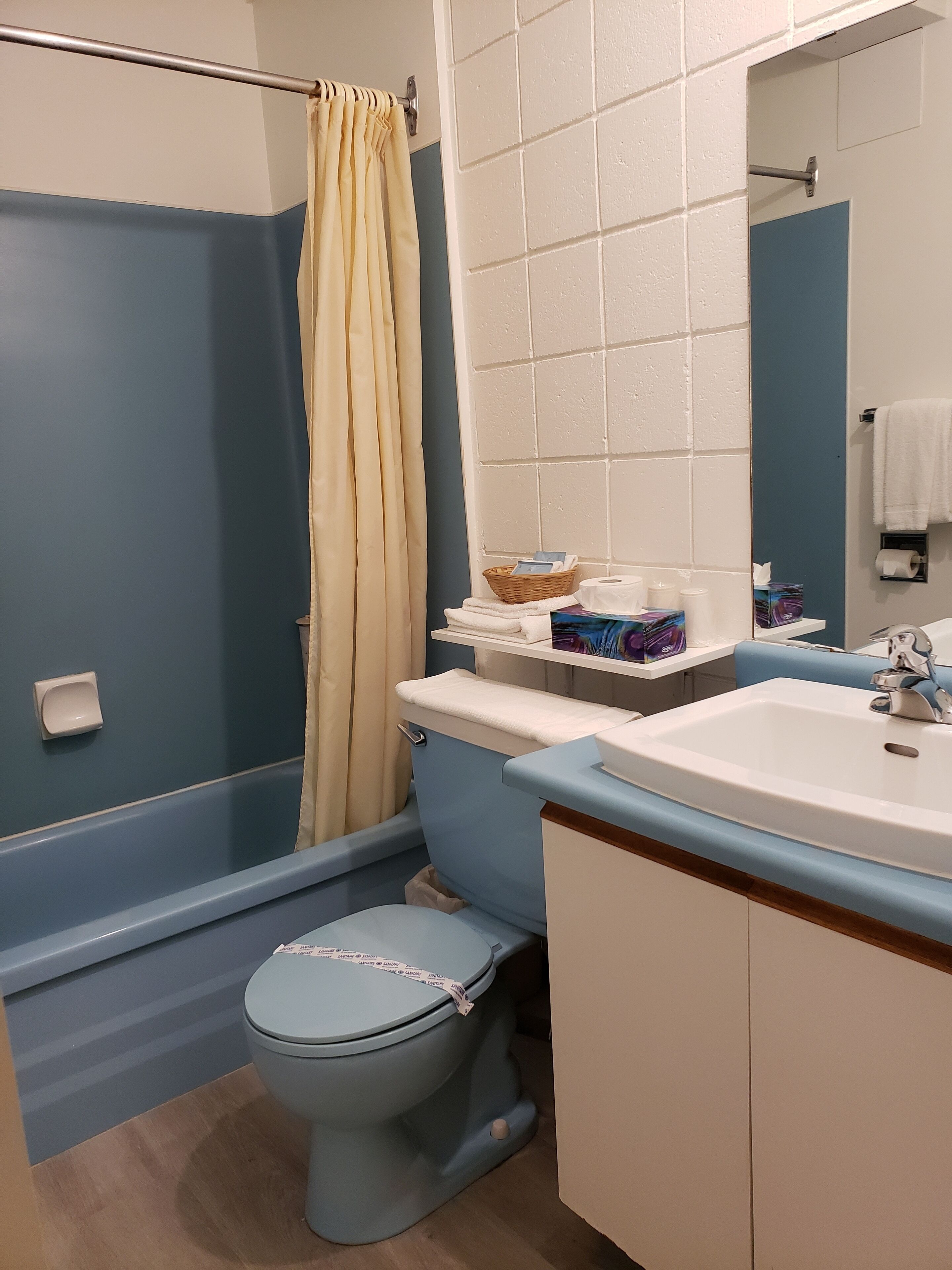 A bathroom with a blue toilet, a white sink, and a shower curtain.