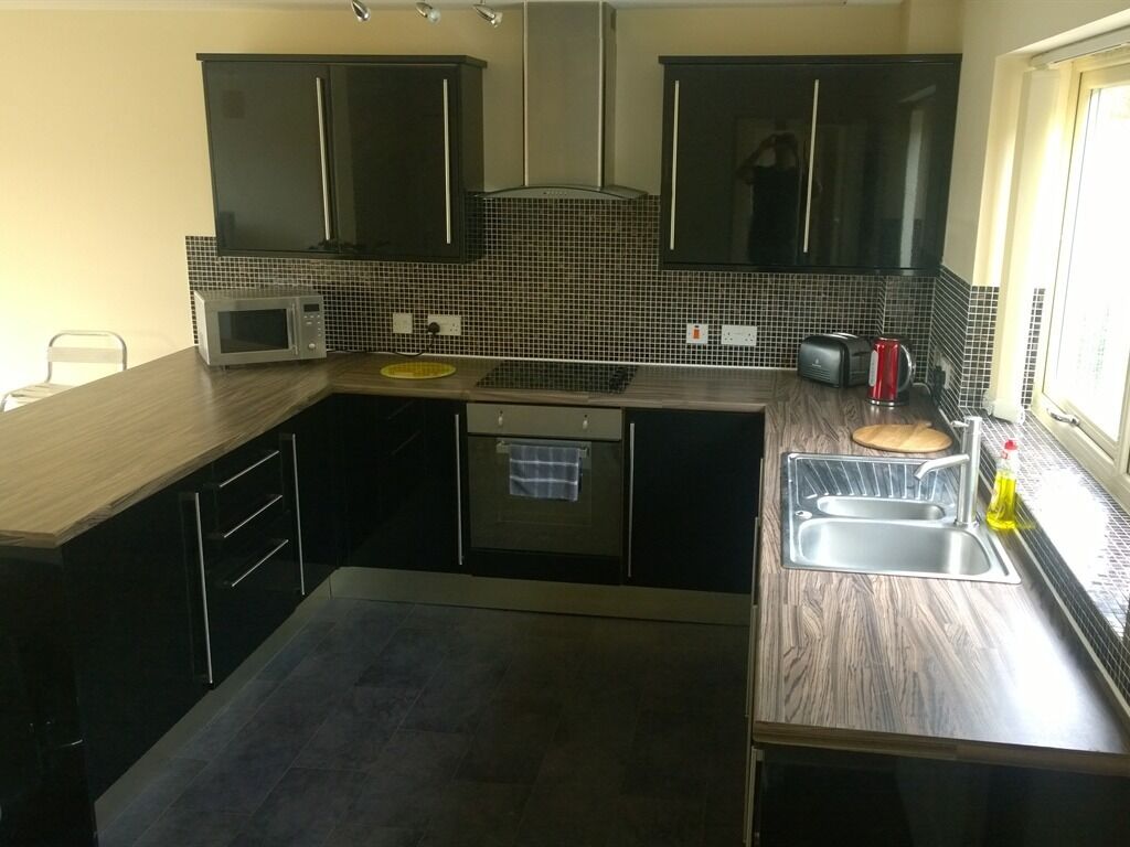 A compact kitchen with dark cabinets, a microwave, a sink, and a window.